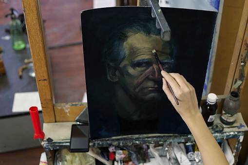 Artist painting photo from tablet on canvas