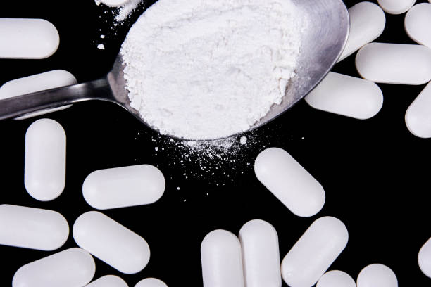 istock Scattered tablets on a black background, along with a spoon full of powdered tablets 1190704898
