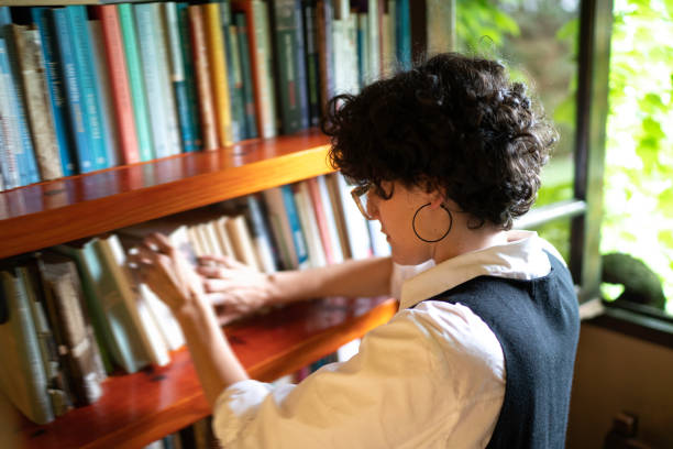 istock Woman searching for a book in a bookshelf 1190717042