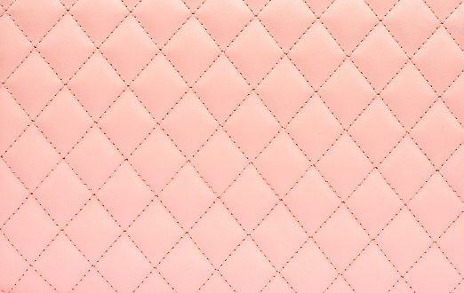 Natural leather background colored in pink and sewn in the form of rhombus. Top view, copy space .