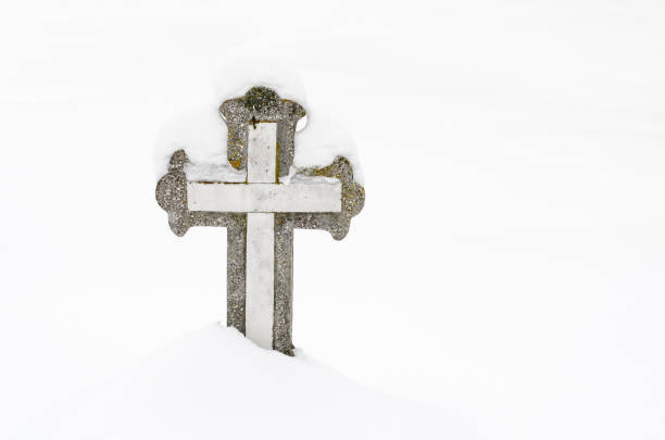 христианский каменный крест на кладбище, покрытом снегом. - stone cross стоковые фото и изображения