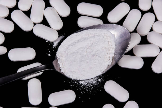 istock Scattered tablets on a black background, along with a spoon full of powdered tablets 1190721083