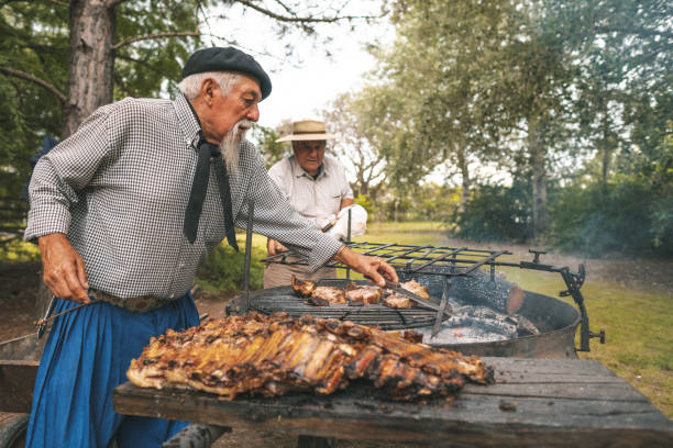 hommes préparant un barbecue de côte dans le bois de feu - argentinian ethnicity photos et images de collection