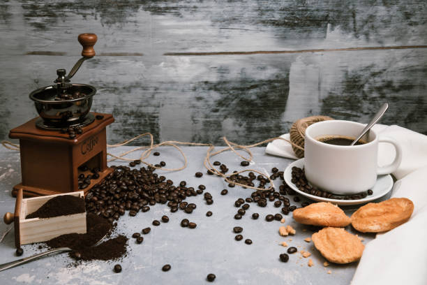 istock Coffee cup, with coffee grinder and coffee beans with ground powder on table. Top view Hot coffee and pastries on a old kitchen table. background concept Coffee cup and coffee grinder with other accessories. 1190746512
