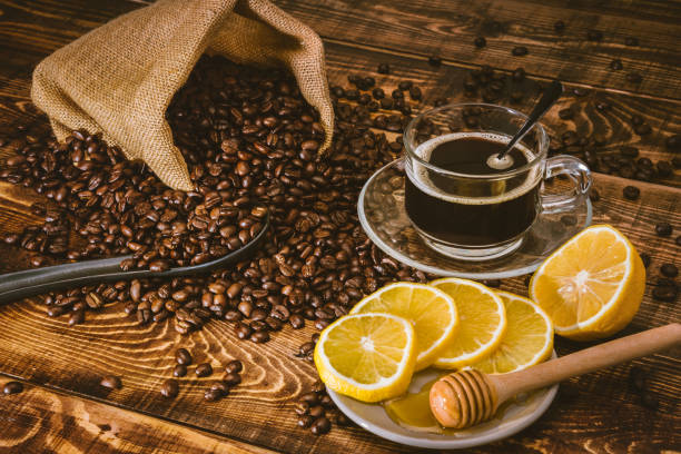 kaffeetasse und bohnen auf altem küchentisch. draufsicht mit kopierraum für ihren text. kaffeebeutel und mit in scheiben geschnittenen "u200b"u200blemons auf holztisch. schwarze kaffeebohnen. - black coffee fotos stock-fotos und bilder