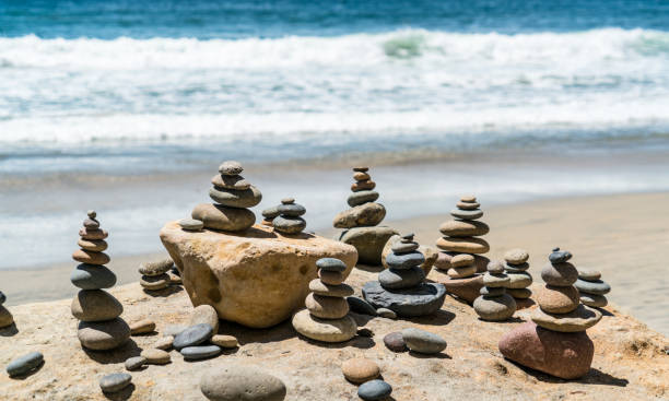 wellen stürzen am strand mit ruhigen felshaufen - stone stability balance zen like stock-fotos und bilder