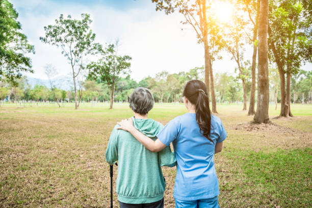 krankenschwester hilft seniorin, durch den park zu gehen - aging process morning outdoors horizontal stock-fotos und bilder