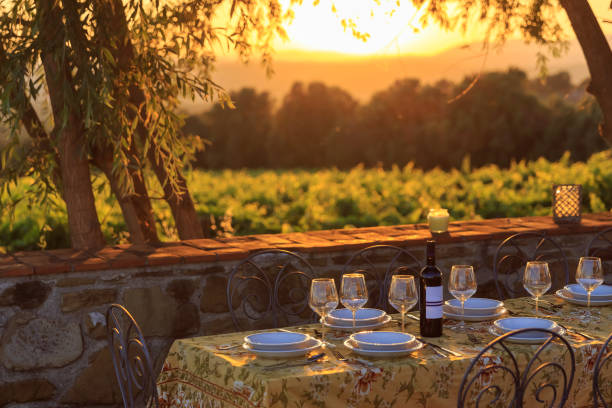 イタリアのブドウ園の背景を持つ屋外テーブル - ワインボトル 写真 ストックフォトと画像