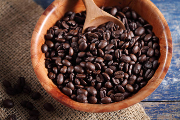istock Coffee beans in wooden cup on rustic wooden table with a blank space for a text, Coffee in cup on loft background 1190761416