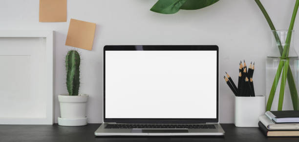 istock Modern workplace with open blank screen laptop computer with office supplies 1190769305