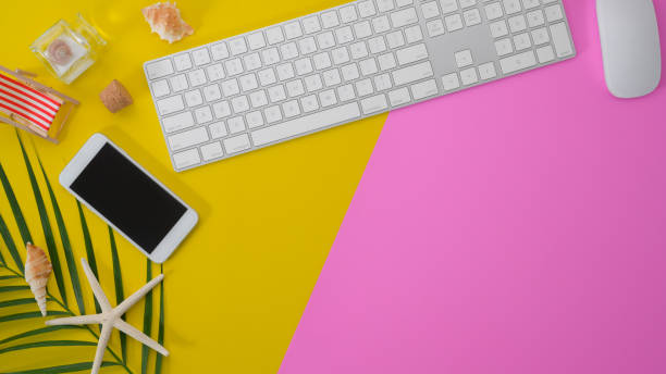 istock Colourful summer workspace with keyboard computer and smartphone on pink and yellow desk 1190769898