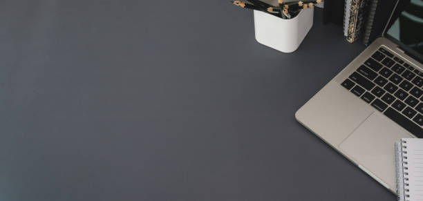 istock Top view of modern workplace with laptop computer and office supplies on dark grey table 1190770004
