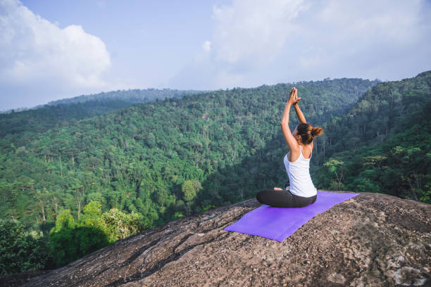 Asian women relax in the holiday. Play if yoga. On the Mountain rock cliff. Nature of mountain forests in Thailand. Young woman practicing yoga in the nature female happiness. exercise yoga las mujeres asiáticas se relajan en las vacaciones. juega si yoga. en el acantilado de la roca de la montaña. naturaleza de los bosques de montaña en tailandia. mujer joven practicando yoga en la naturaleza felicidad femenina. ejercicio yoga