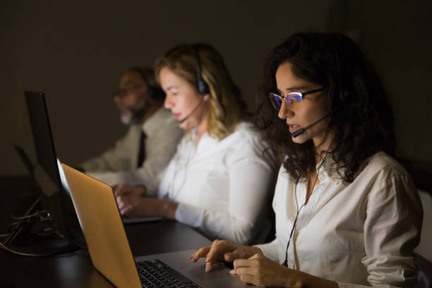 istock Serious teleworkers in headsets in dark office 1190774205