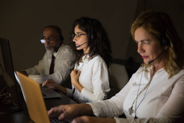 istock Teleworkers in headsets in dark office 1190774400