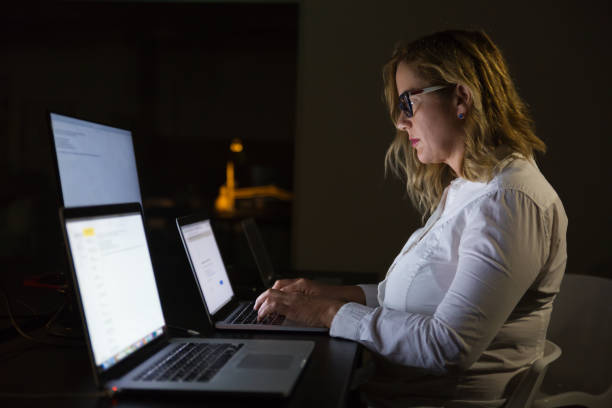 istock Businesswoman using laptop in dark office 1190775389