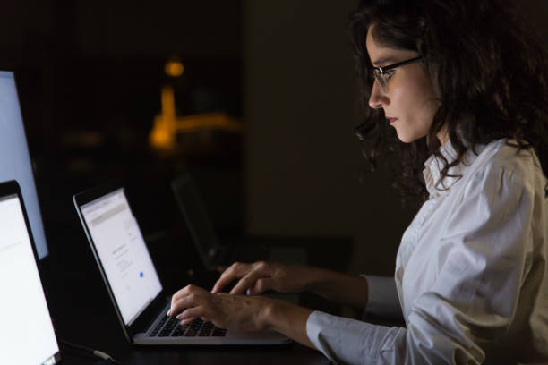 istock Serious businesswoman using laptop in dark office 1190775480