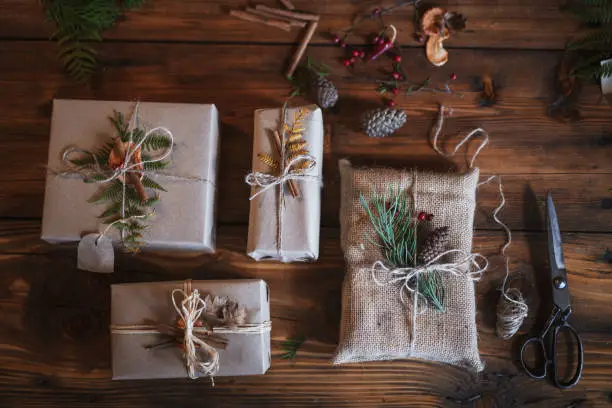 Unrecognizable male hands wrapping Christmas presents with natural materials, plastic free, organic wrapping with paper.