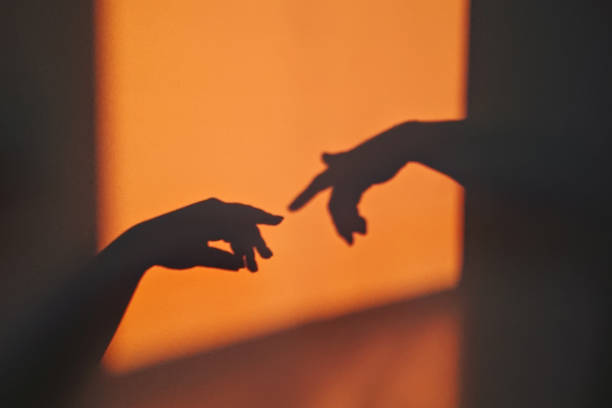 Abstract shadow silhouette of gesture touch by humans palms from sunbeam on wall