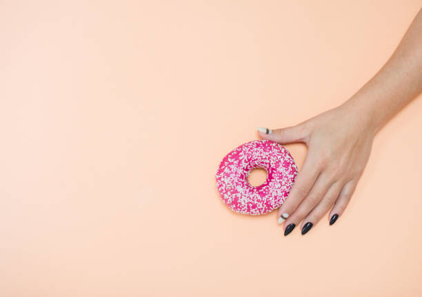 istock Appetizing donuts with icing on a colored background with female hands with a beautiful manicure. 1190782777