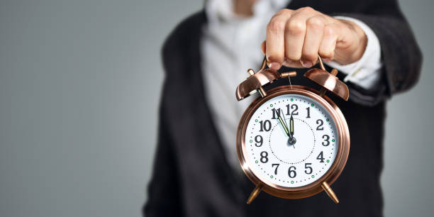 istock Businessman holding a clock that shows five to twelve 1190792476