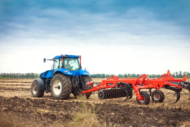 moderner traktor auf dem feld während der pflanzung. das konzept der agrarindustrie. - landwirtschaftliches gerät stock-fotos und bilder