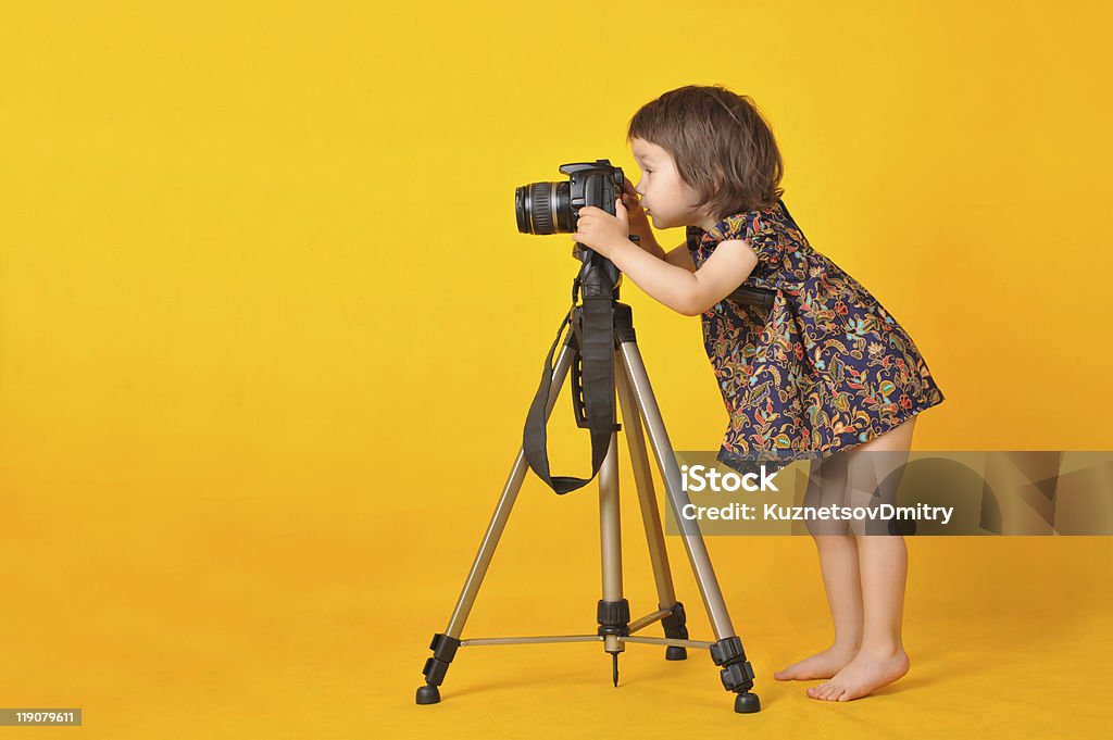 Little girl holding photo camera Portrait of little girl holding photo camera isolated on yellow background Photographer Stock Photo