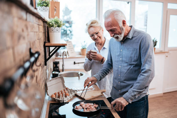 istock Senior couple in the kitchen making bacon and eggs for breakfast. 1190798299