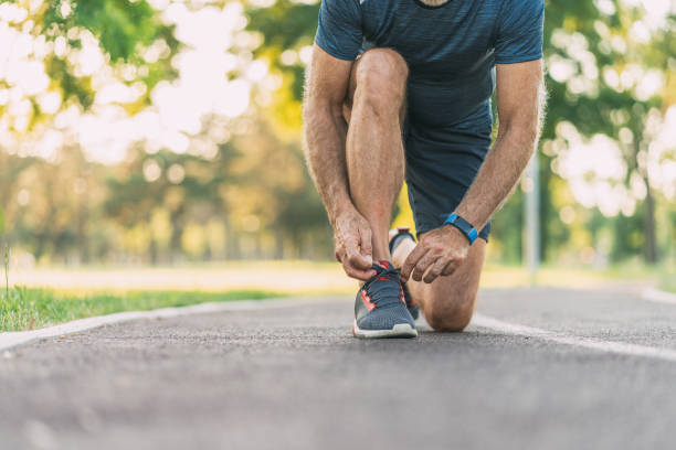 sportsman tying shoelaces - shoe tying adult jogging imagens e fotografias de stock