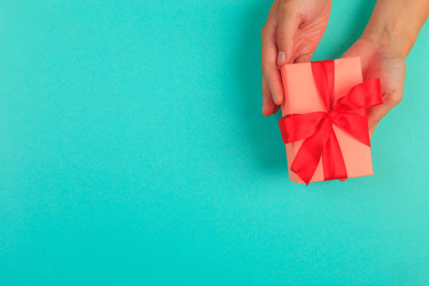 istock gift in female hands on a colored background top view. 1190799475