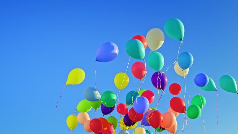 SLO MO LD Colourful balloons floating across the blue sky