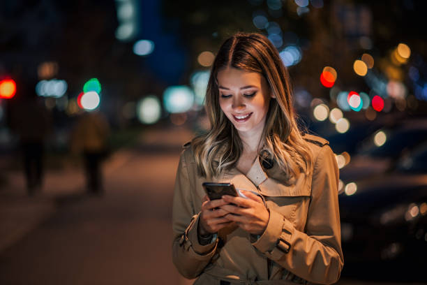 夜にスマートフォンを使って笑顔の若い女性の肖像画。 - タクシー 写真 ストックフォトと画像