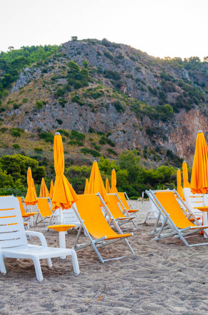 istock White plastic and metal construction with yellow fabric deckchairs together with yellow umbrellas on the sand beach of Tyrrhenian sea with mountains on background in Italy 1190805527