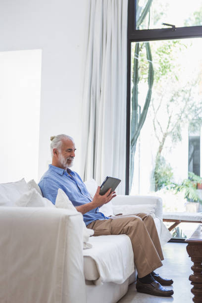 istock Senior man browsing tablet, drinking coffee in his living room 1190806334