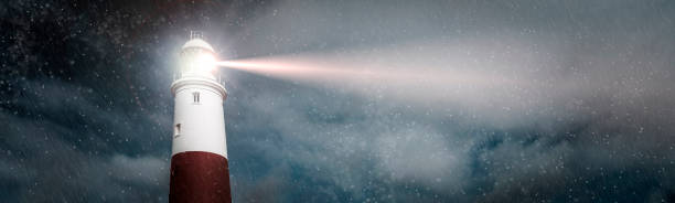 istock Large lighthouse with bright search light on a dark and stormy night panoramic 1190807461