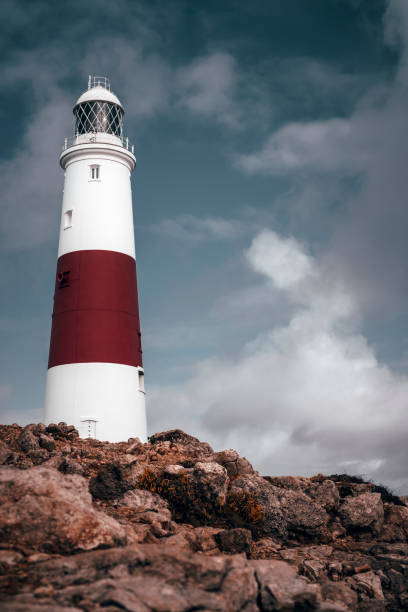 istock Large lighthouse on a clear blue sky day with white clouds at sunrise in England 1190808040