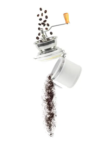 Coffee beans and ground powder falling from manual grinder. Ingredient for hot drink isolated on white background