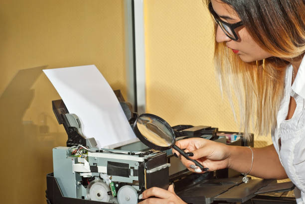 la ragazza con una camicia bianca stampa una foto. donna che guarda la stampante con lente d'ingrandimento. l'assistente controlla gli elementi della stampante. - photobusiness foto e immagini stock