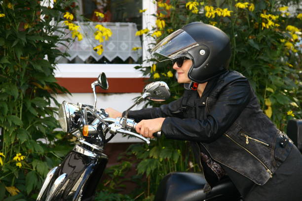 istock Woman with motorcycle in front of house with front yard 1190808933