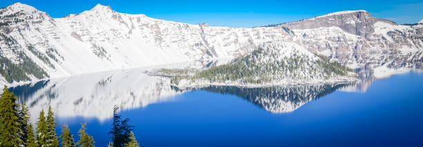 istock Panoramic green pine tree lush and reflection of snowcap mountain with Wizard Island on Crater Lake 1190813811