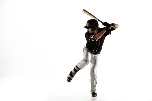 Baseball player, pitcher in a black uniform practicing on a white background. Baseball player, pitcher in a black uniform practicing and training isolated on a white background. Young professional sportsman in action and motion. Healthy lifestyle, sport, movement concept. men baseball baseball cap baseball bat stock pictures, royalty-free photos & images