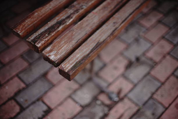 Old wooden bench with peeling paint, top view, blurred tiled floor.