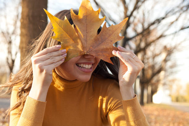 istock Young woman having fun in the park with leaf on her face 1190828955
