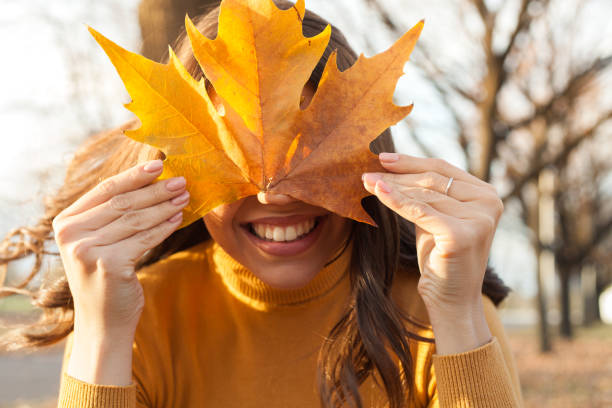 istock Young woman having fun in the park with leaf on her face 1190829086