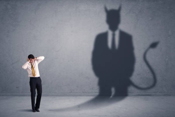 istock Business man looking at his own devil demon shadow concept 1190829331