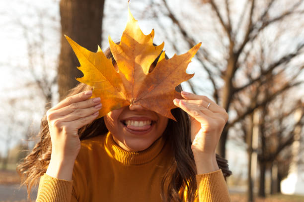 istock Young woman having fun in the park with leaf on her face 1190830170