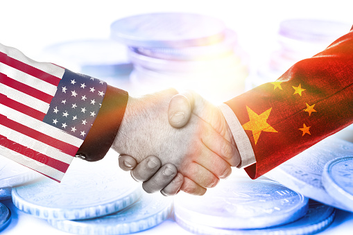 Print screen of USA and China flag on shirts of businessman hand shaking.It is symbol of economic tariffs trade war and tax barrier between United States of America and China.