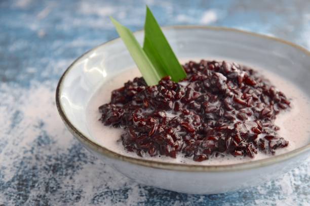 Bubur Ketan Hitam, dessert indonésien. Bouillie noire de riz gluant avec le lait de coco, le sucre de palme et la feuille de pandan. - Photo