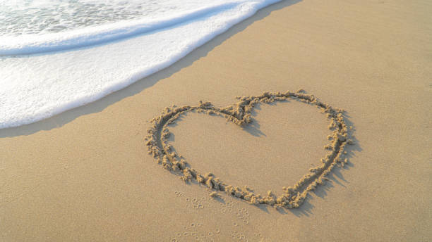 istock Valentine concept.Image of A heart shape on sandy beach 1190844059