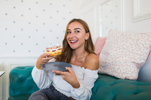 Cake shop owner posing on the couch holding donut with strawberries